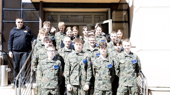 Zdjęcie przedstawia klasę mundurową, uczniowie stoją przed budynkiem Wydziału Prawa